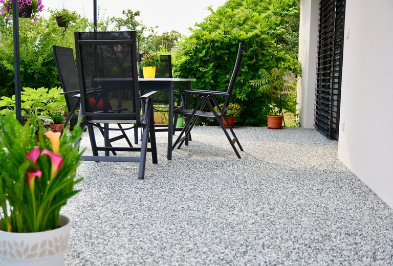 Beautiful terrace with decorative natural stone floor, potted calla lily and table with chairs