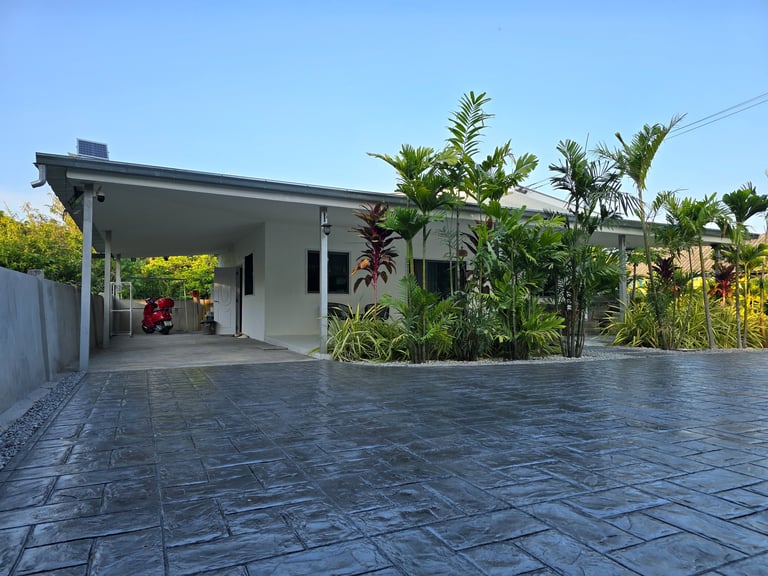 Modern stamped concrete driveway with lush greenery landscaping